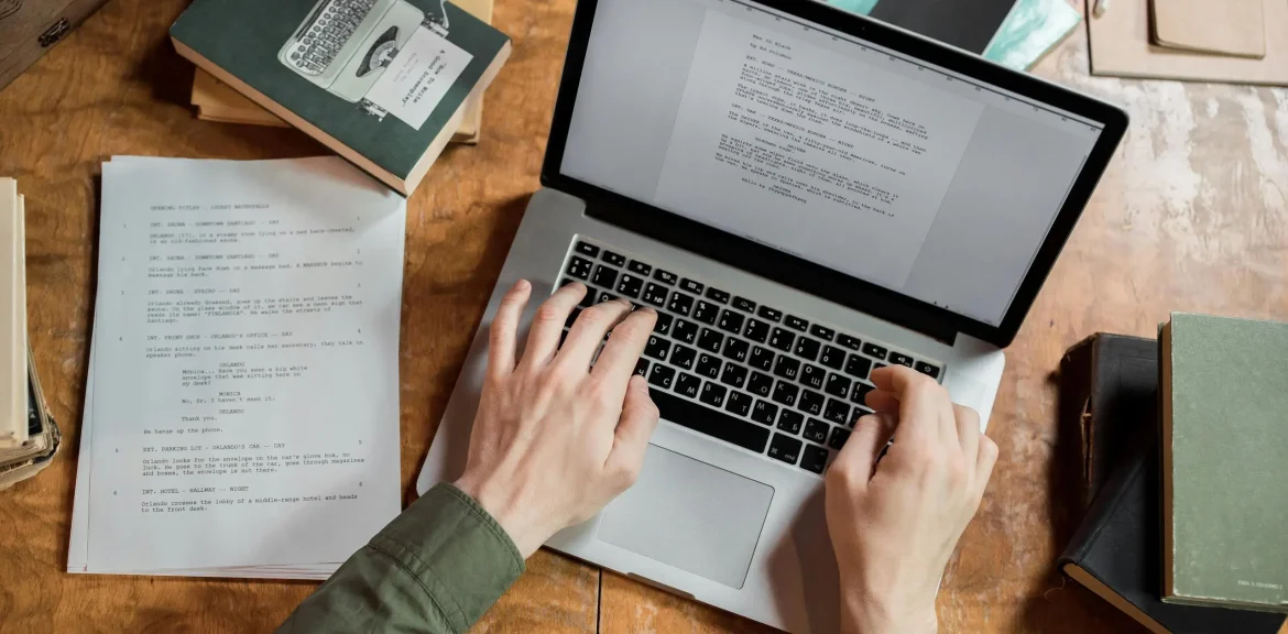 Rédacteur web SEO travaillant sur son ordinateur portable à partir de notes et de documents
